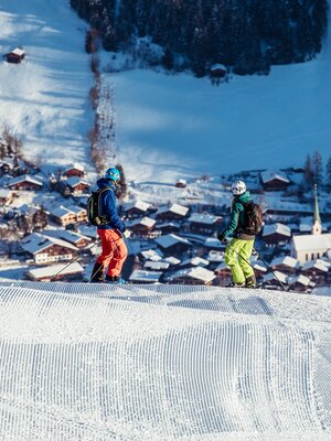 Zwei Skifahrer schauen von der Skipiste aus runter ins Dorf Alpbach